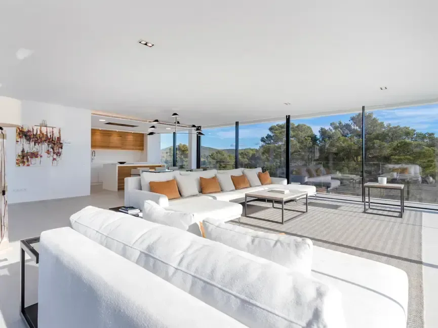 Salón con sofás blancos y terraza abierta al paisaje.