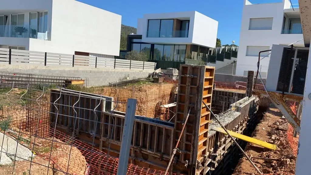 Obra en ejecución con excavación, armaduras de acero y apuntalamiento.